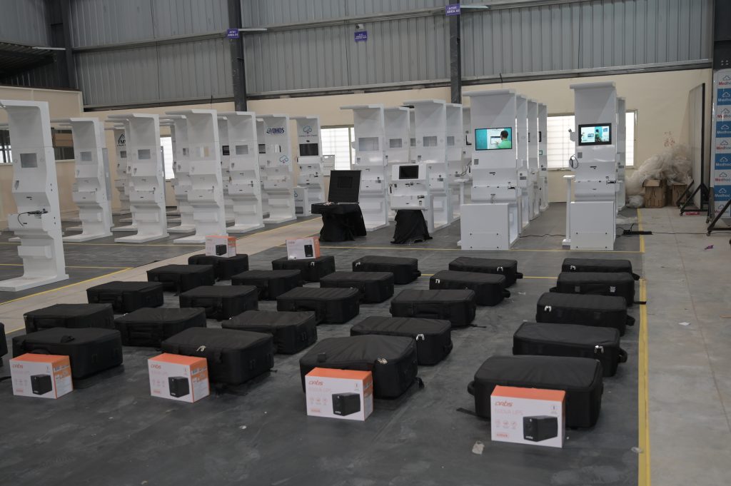 Assembled kiosks beside boxed diagnostic devices and packed cases ready for dispatch
